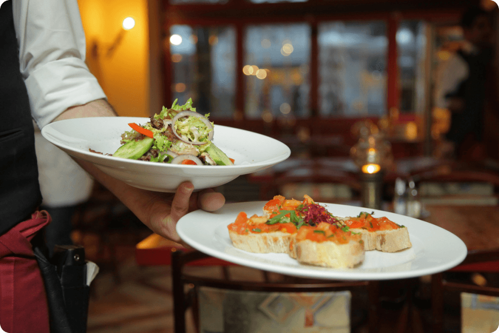 Waiter serving freshly prepared dishes to guests in a well-organized restaurant