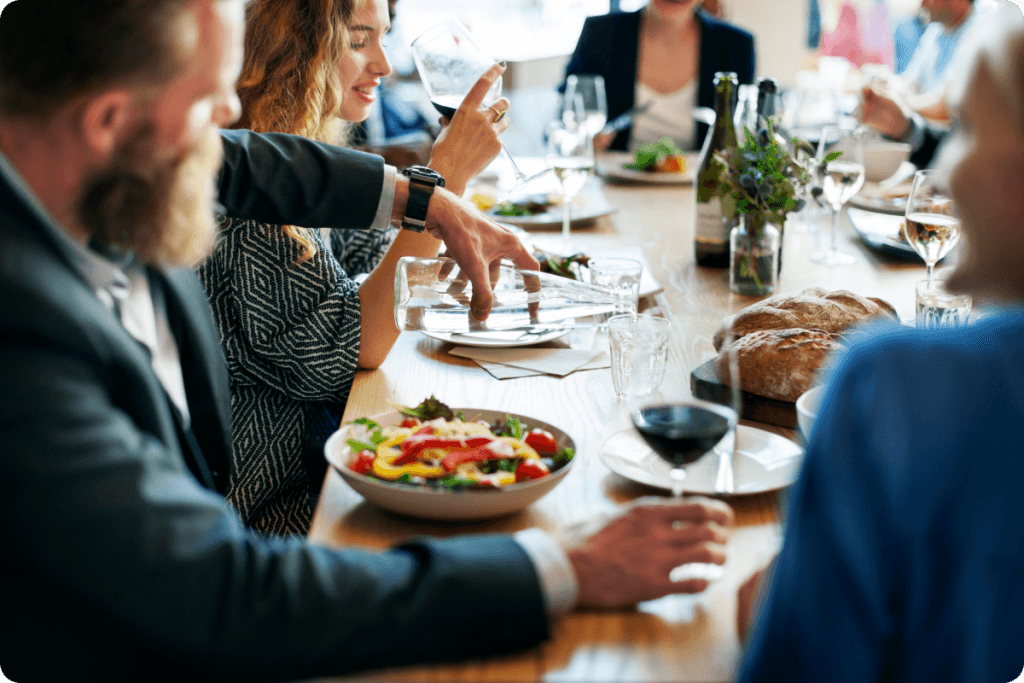 Happy team raising glasses during a corporate dinner at a fine-dining restaurant