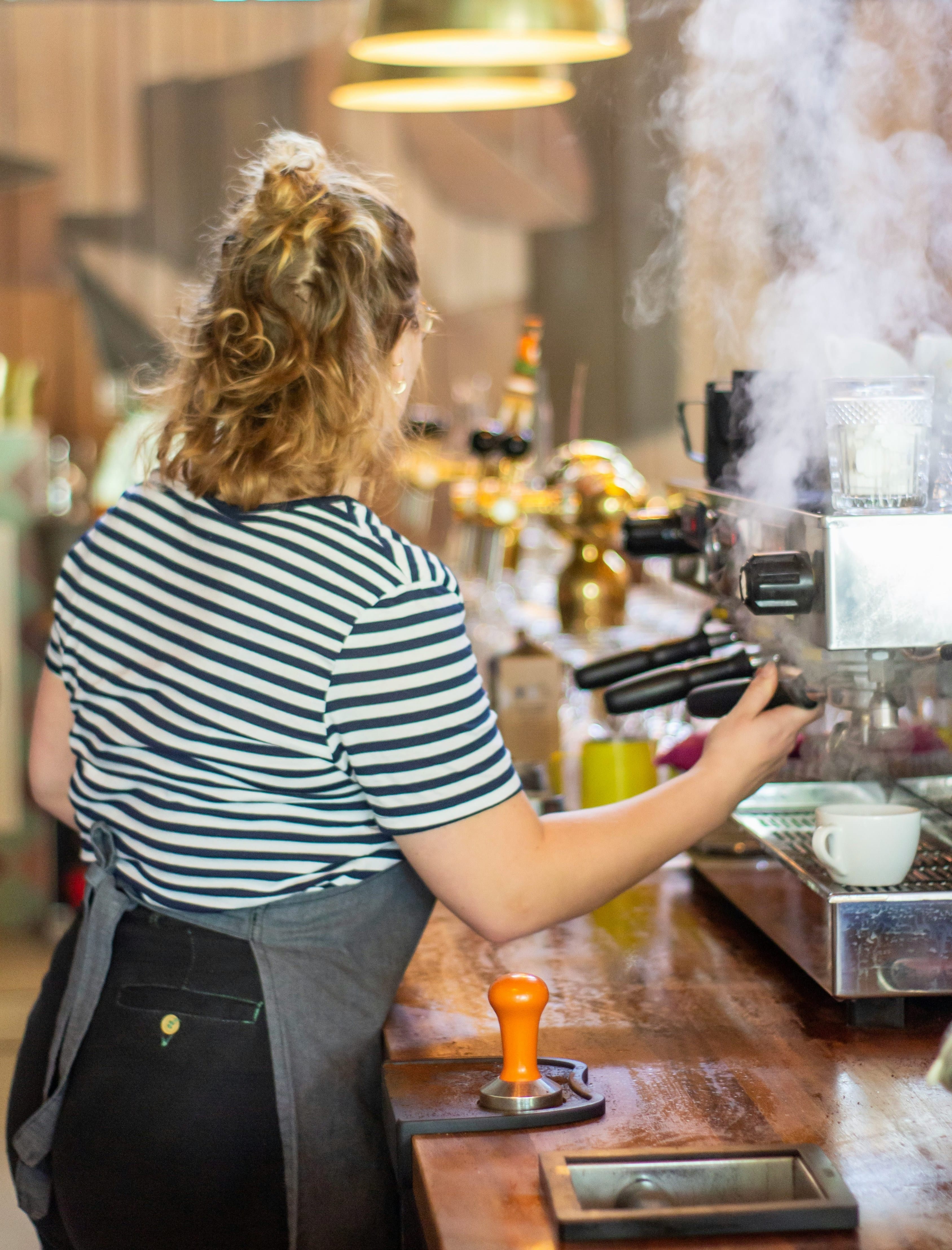 Barista pulling an espresso shot by the coffee machine