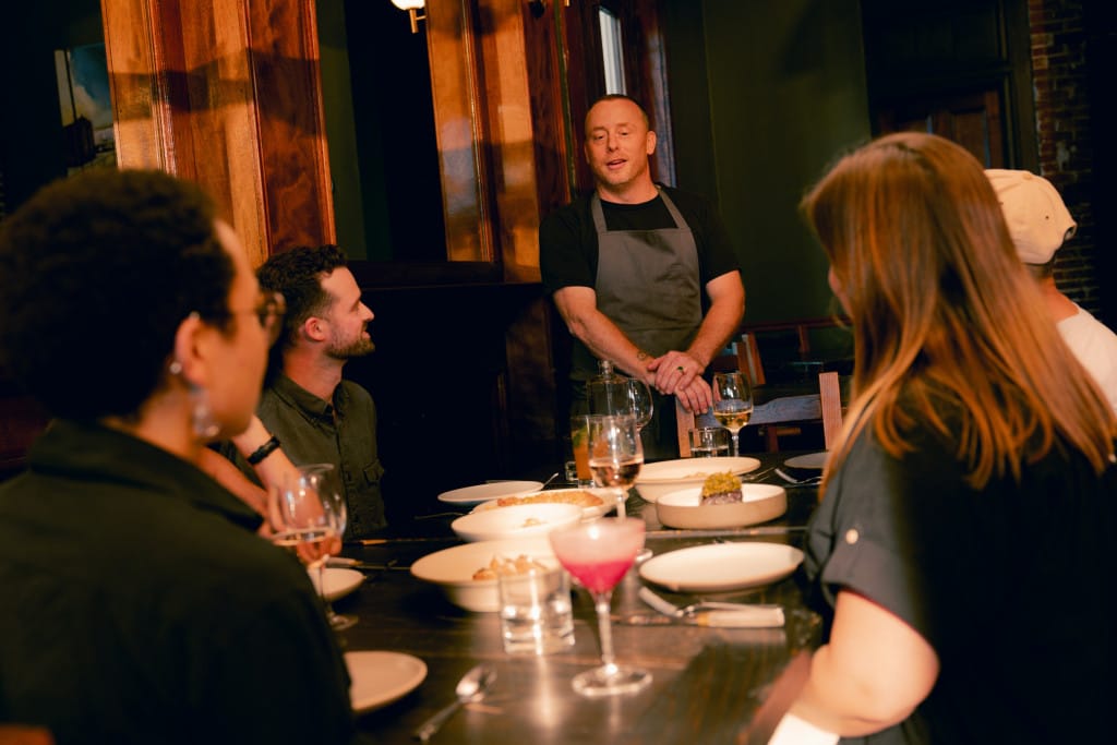 Restaurant owner sharing with a group of customers at the table.