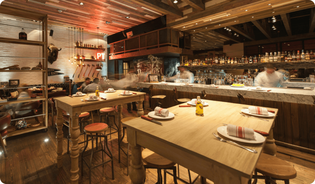 Large dining room with chefs busy in the kitchen and diners waiting to be served.