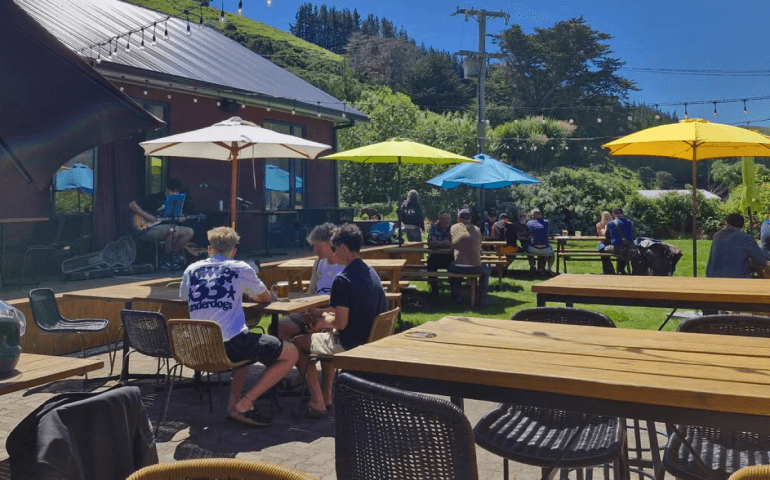 Pub goers gathering at a table with umbrellas.