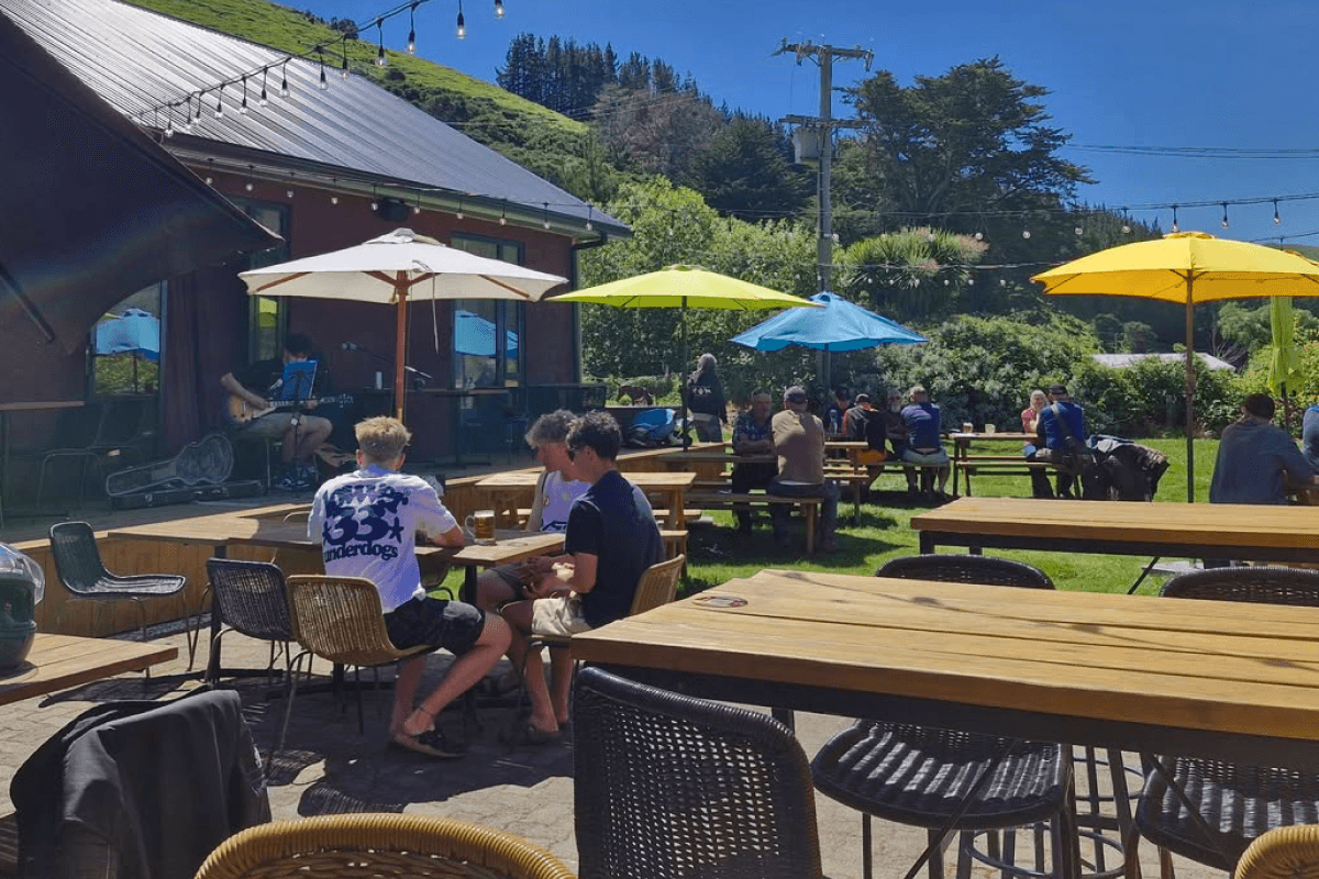 Pub goers gathering at a table with umbrellas.