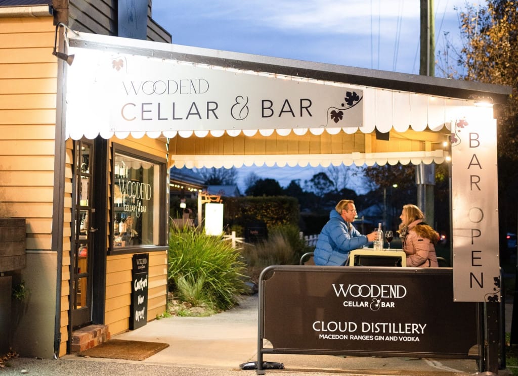 The view of Woodend Cellar storefront, with a couple dining outdoors.