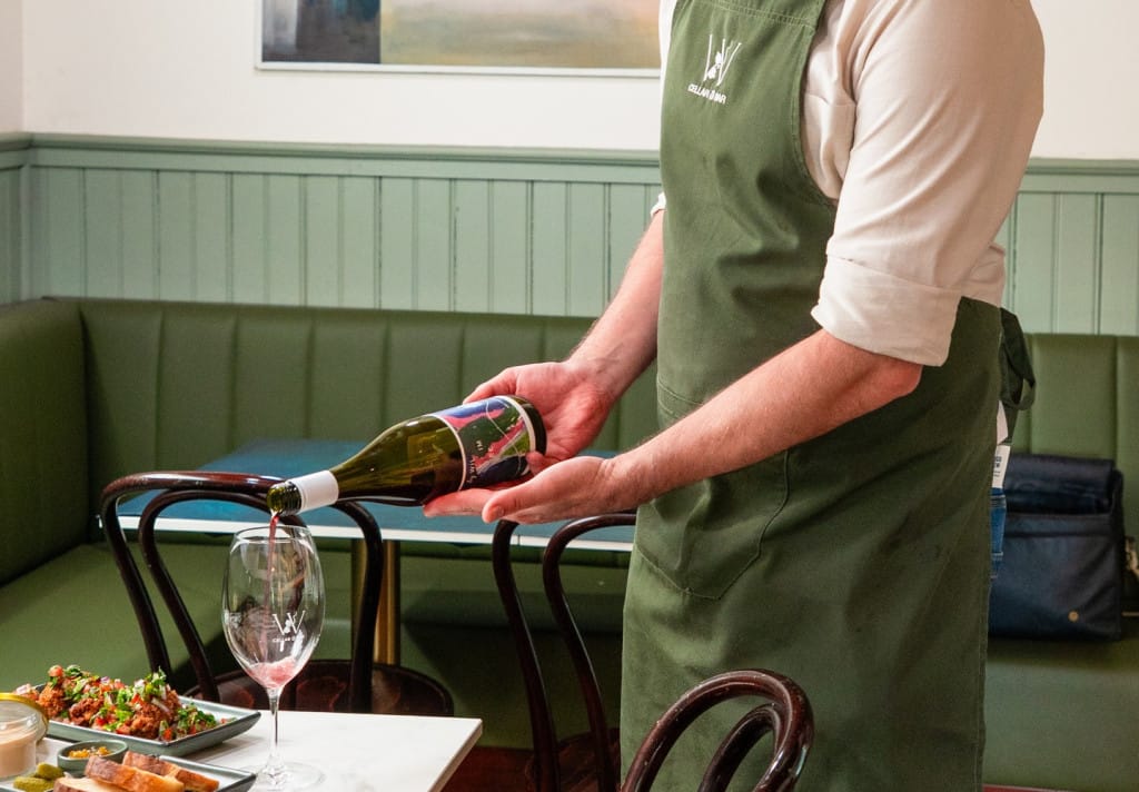 Server pouring wine into a glass at the table at Woodend Cellar