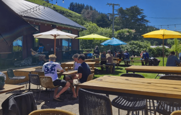 Pub goers gathering at a table with umbrellas.